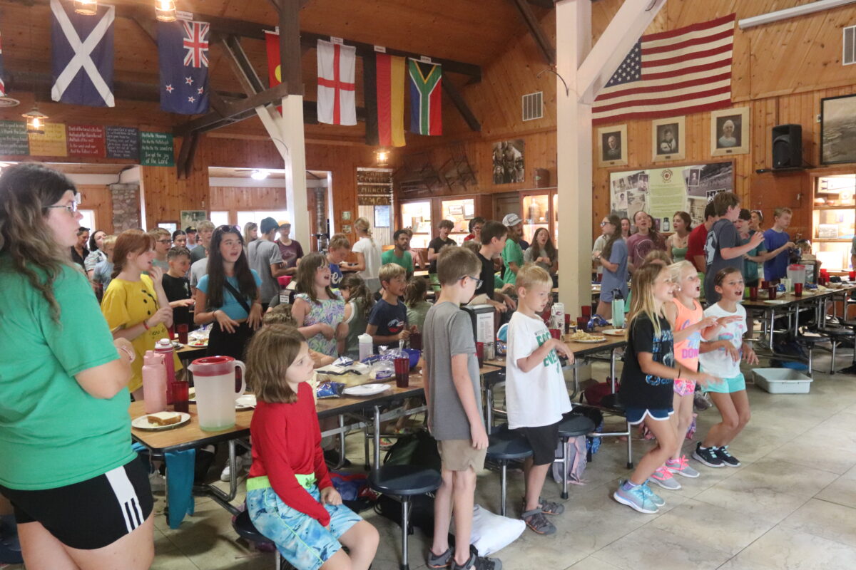 Image of several campers singing and dancing in the dining hall.