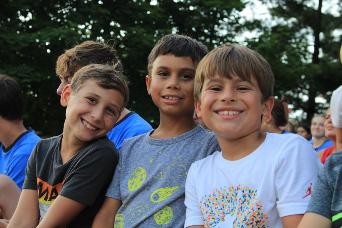 Three young boys sitting together posing for a photo.