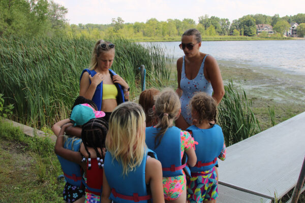Two camp counselors preparing their group to go swimming.